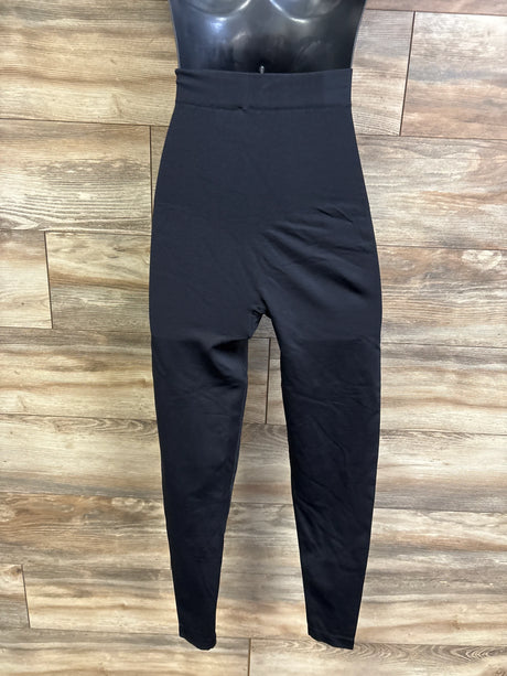 Front view of black maternity shapewear leggings showing high-rise tummy panel and tapered legs on wood background