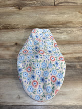 Floral fleece baby hat with blue and pink flowers on light background, laid on wood floor