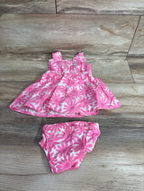 Top down view of pink floral baby dress and matching bloomers showing daisy print, ruffled straps and elasticized waist on wood floor