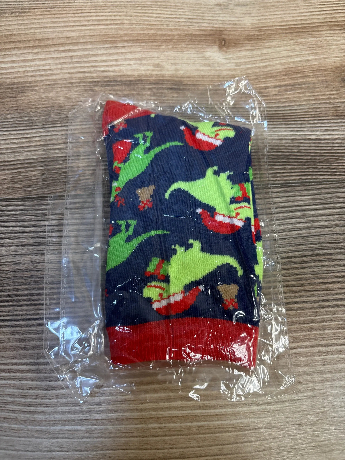 Kids dinosaur socks with green and red print, packaged for resale