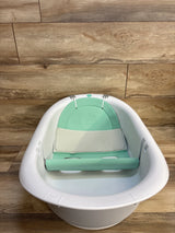 White baby bathtub with mint green cushioned insert on wood floor, ideal for infant bath time