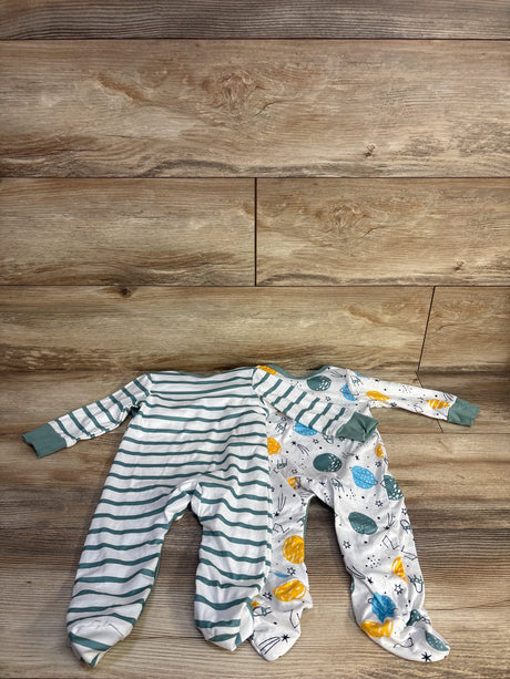 Top view of 2 newborn footed coveralls: teal striped and white with planet print, on wood background
