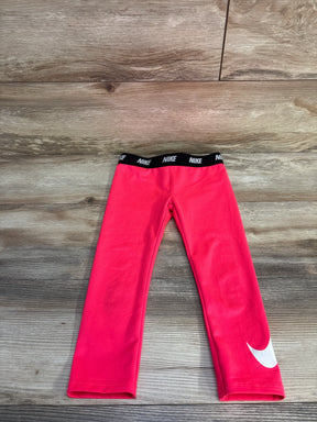 Front flat lay of girls pink Nike Dri-Fit leggings 4T showing black elastic NIKE waistband and white Swoosh on wood floor
