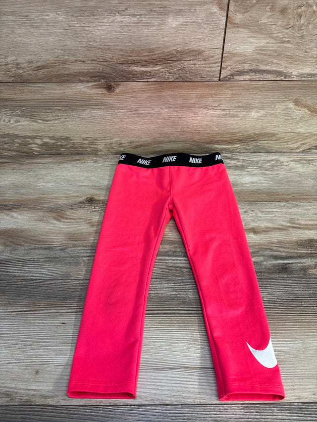 Front flat lay of girls pink Nike Dri-Fit leggings 4T showing black elastic NIKE waistband and white Swoosh on wood floor