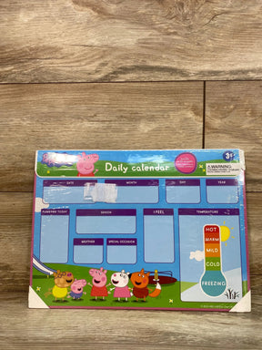 Front view of Peppa Pig magnetic daily calendar showing labeled date/month/day/year boxes, temperature thermometer, and character illustrations on wood floor background