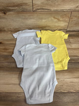 Back view of three infant short-sleeve bodysuits showing two light blue and one yellow, laid flat on wood background