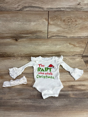 White baby onesie with 'The BABY who stole Christmas' print, ruffled sleeves, and matching headband on wood floor