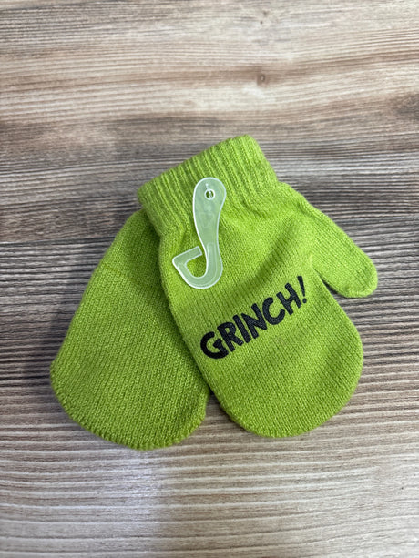 Green children's knit mittens with the word GRINCH printed on one mitten on wooden surface