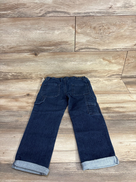 Children's dark blue denim jeans with rolled cuffs and back pockets on wood floor background