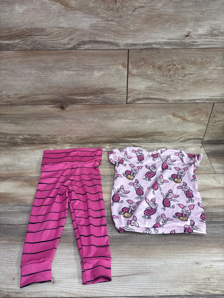 Top-down view of pink Disney two-piece shirt and pants set for size 2/3T, with striped pants and character-print shirt on a wood floor