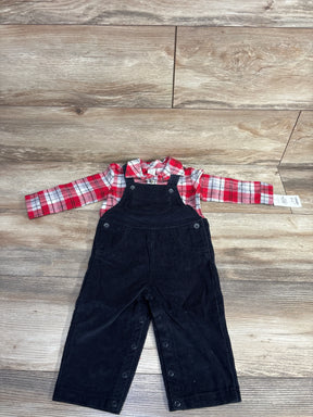 Baby outfit with red plaid shirt and black corduroy overalls on wood floor