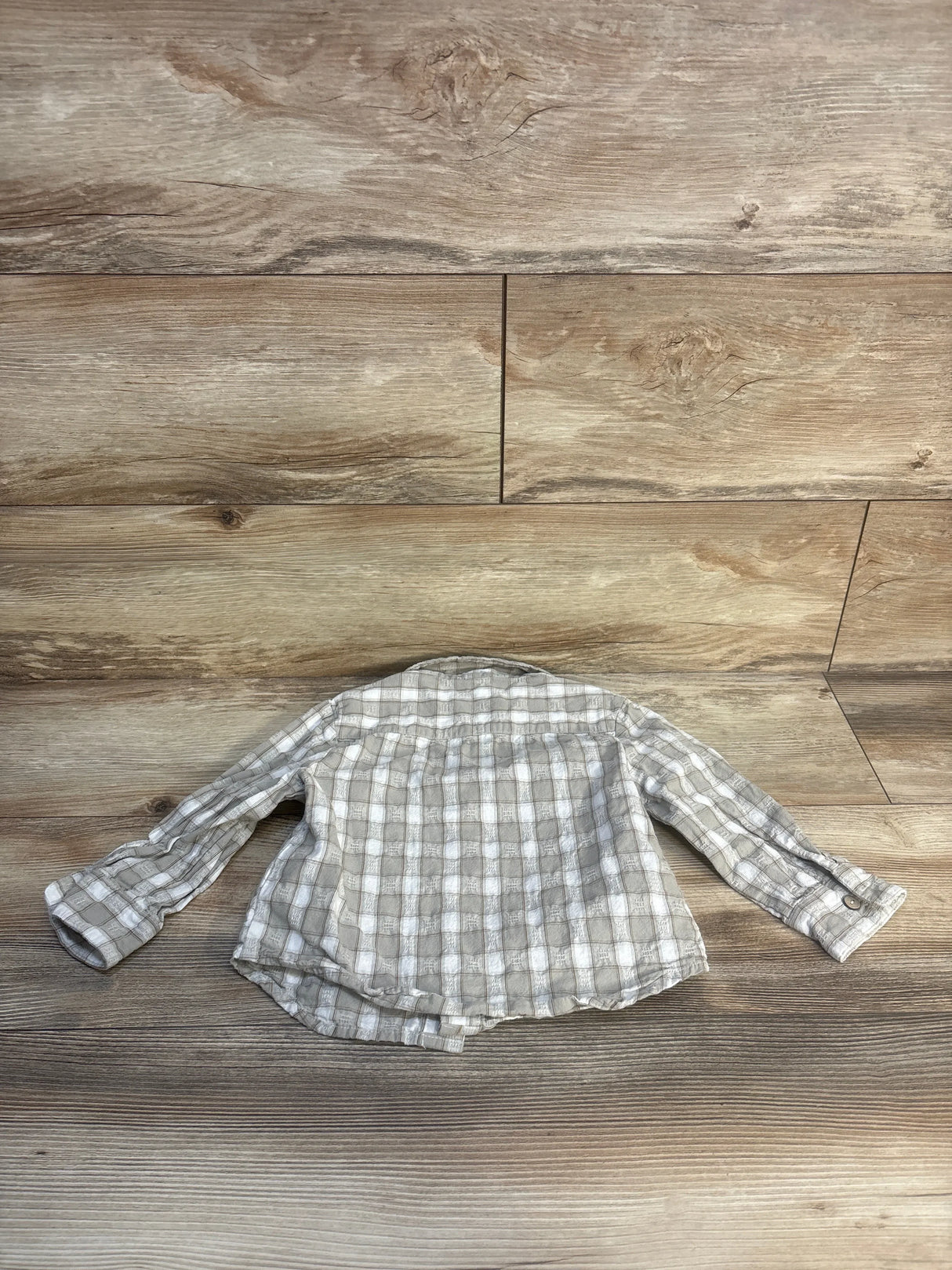 Plaid long sleeve toddler shirt in neutral colors on wood background