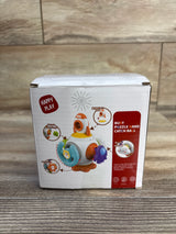 Front view of Happy Play Puzzle Busy Ball box showing toy illustration and red product label on wooden floor background
