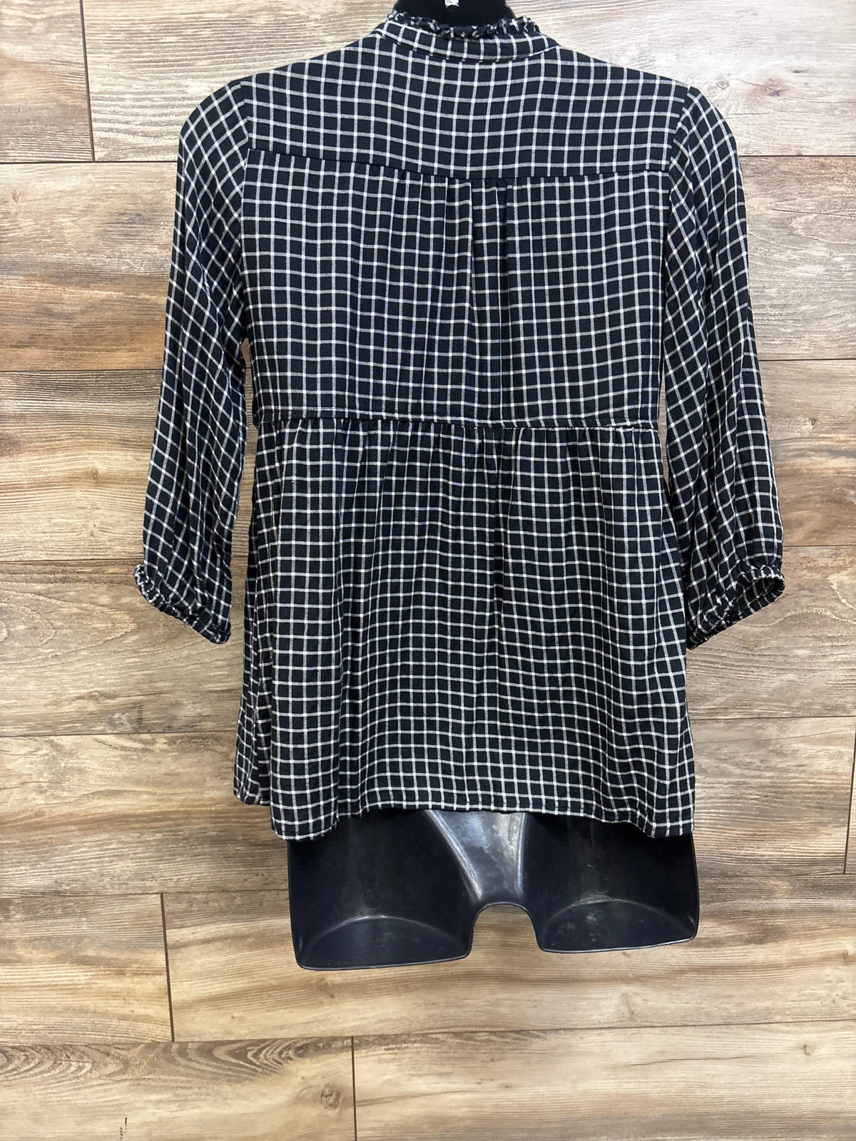 Front view of Isabel Maternity flannel popover tunic with long sleeves and black plaid pattern on wood flooring