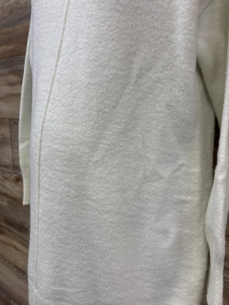 Close-up of Isabel maternity sweater dress in white, size medium, showcasing knit texture with wood flooring background
