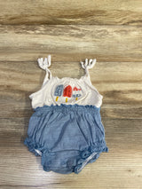 Flat lay of white and blue 4th of July bubble romper with knotted straps, popsicle embroidery, snap crotch on wood