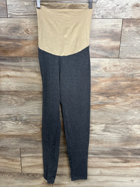 Two-tone maternity leggings with beige high waistband and dark gray legs hanging on wooden wall