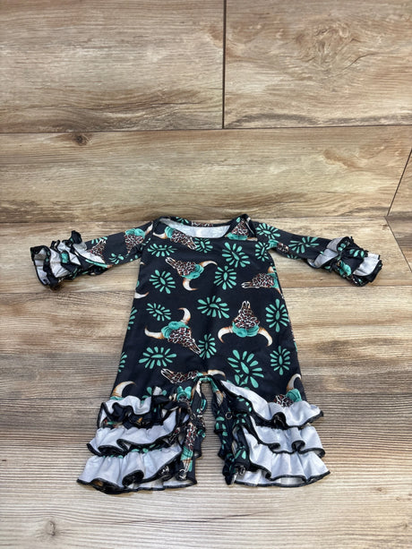 Flat lay of black baby coverall with teal longhorn and floral print, ruffled sleeves and triple ruffle leg cuffs on wood