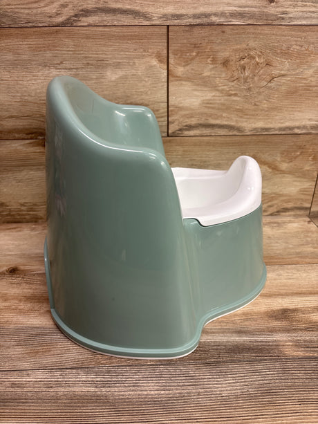 Side view of green BabyBjorn potty chair showcasing its white inner basin against a wood panel background