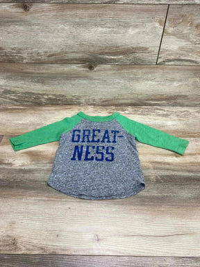 Flat lay of Crewcuts raglan toddler shirt showing green sleeves, grey heather body, and blue GREAT-NESS text on wood background