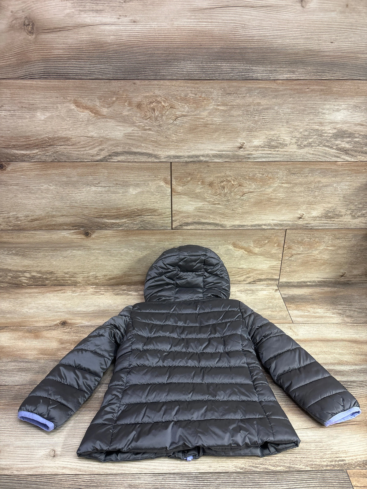 Grey Nike hooded puffer jacket for toddlers laid flat on a wood background