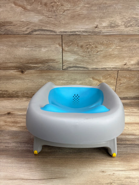 Front view of Skip Hop Baby Bath Tub Moby Recline and Rinse showcasing blue reclined seat and yellow feet with wood backdrop