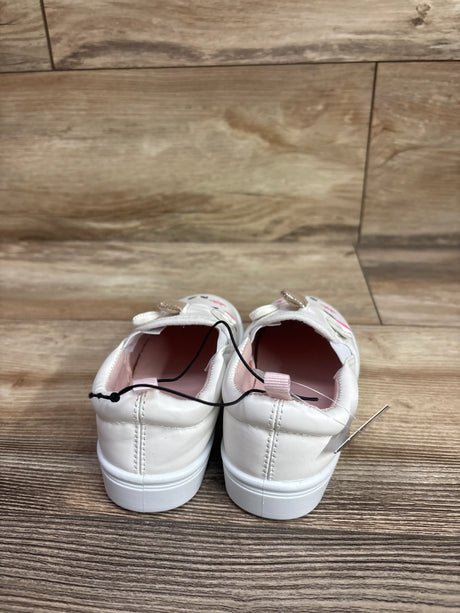 Rear view of Bocca slip-on unicorn sneakers showcasing white uppers and soles with pink interiors on a wood floor