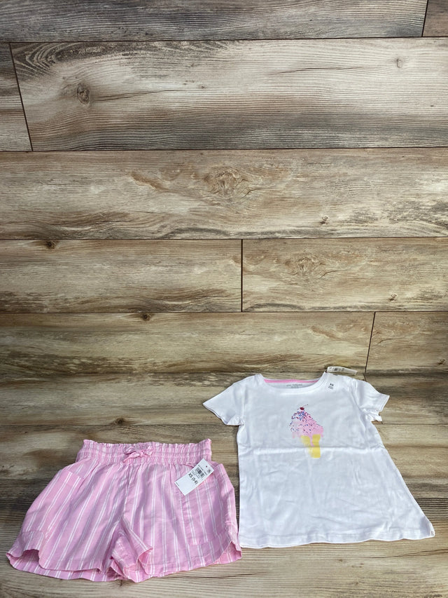 Flat lay of toddler white ice cream tee and pink striped elastic waist shorts on wood floor background
