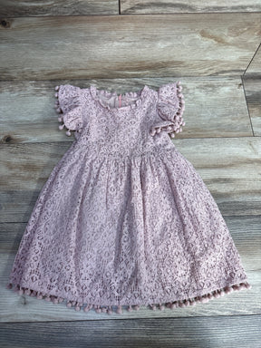 Pink toddler lace dress with pom-pom trim on wooden floor