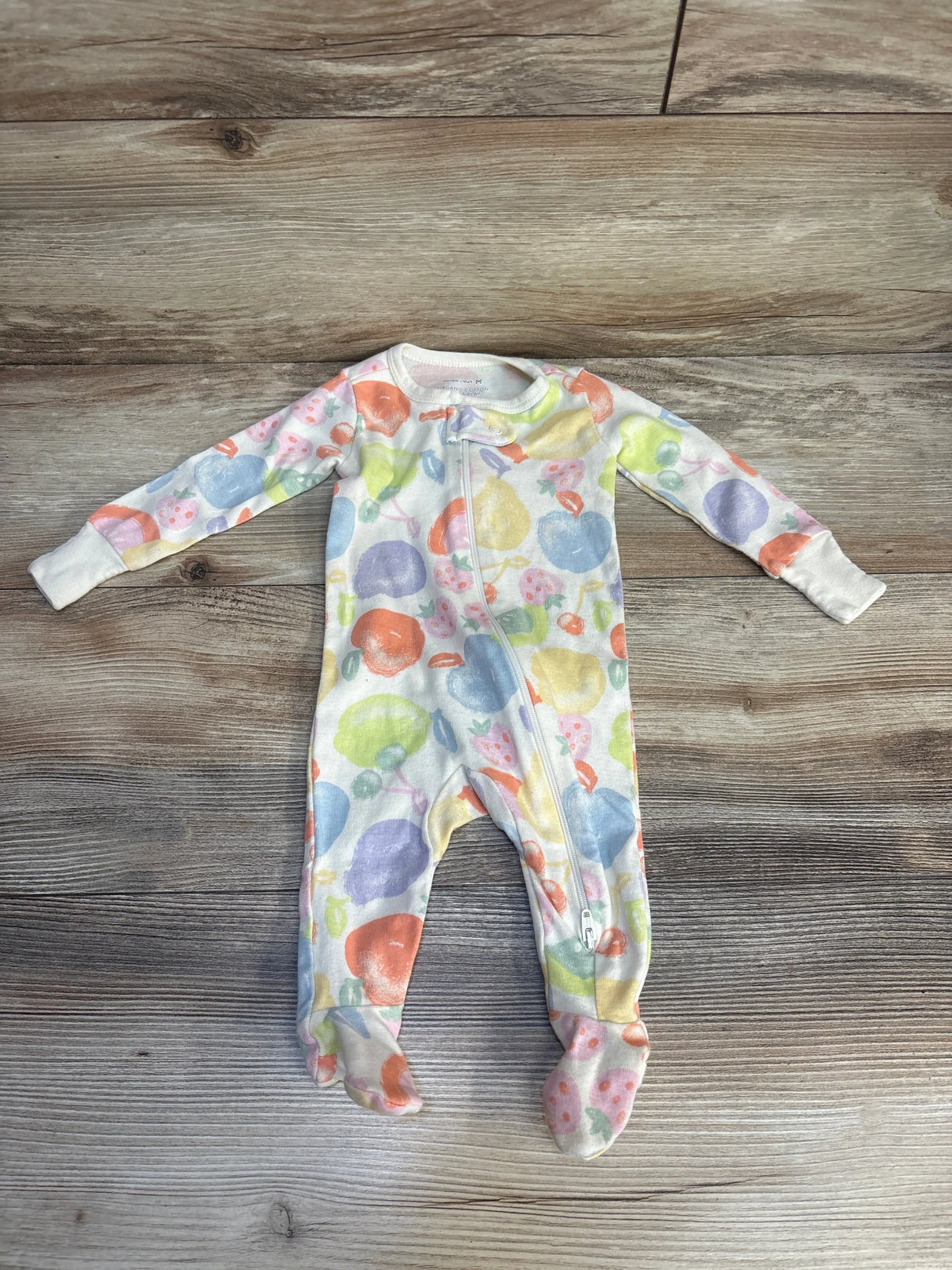 Colorful fruit print baby sleeper with zipper on wood background, long sleeves and footed design