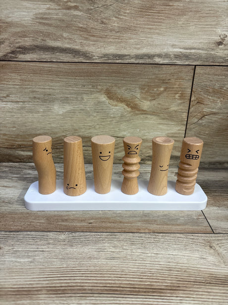 Front view of Lovevery wooden emotion dolls showing six carved figures with different facial expressions on a white base