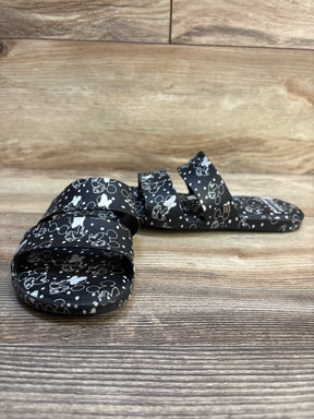 Black children's sandals with white cartoon character prints on wood floor