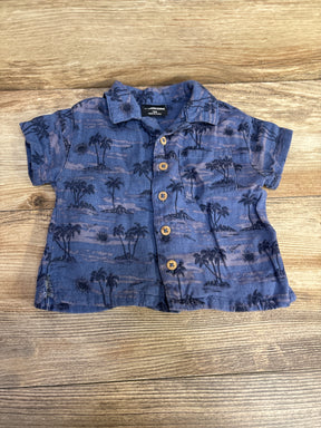 Blue toddler button-down shirt with palm tree print on wooden background