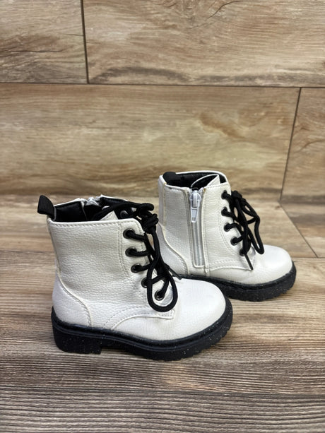 Three-quarter view of Sincerely Jules faux-leather combat boots with black laces, side zippers, and lug soles on wood flooring