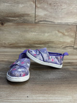 Purple glitter toddler shoes with star pattern, slip-on design, white soles on wood floor