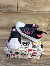 Angled view of Adidas x Hello Kitty Superstar 360 sneakers showing white shell toe and pink logo on Hello Kitty shoebox