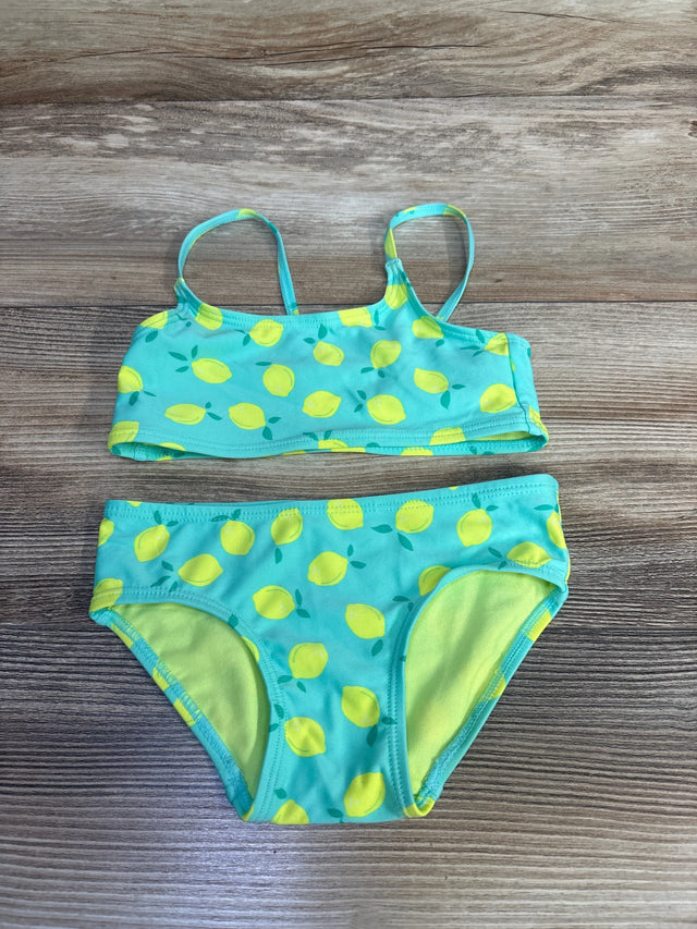 Flat-lay of girls' 2-piece teal lemon-print bikini (2T) showing thin straps and lined full bottoms on wood background