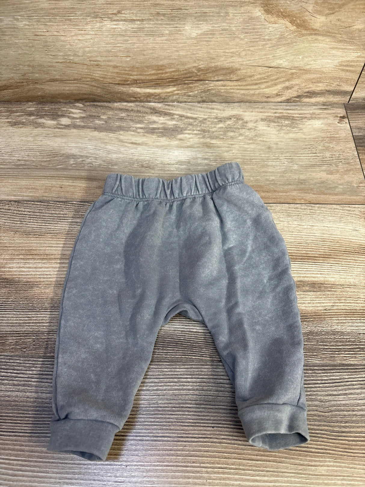 Front flat lay of newborn grey Cat and Jack pull-on joggers showing elastic waistband and cuffed ankles on wood background