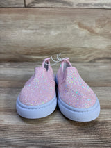 Front view of Cat & Jack Yana toddler slip-on sneakers with pink glitter upper and white rubber sole on wood background