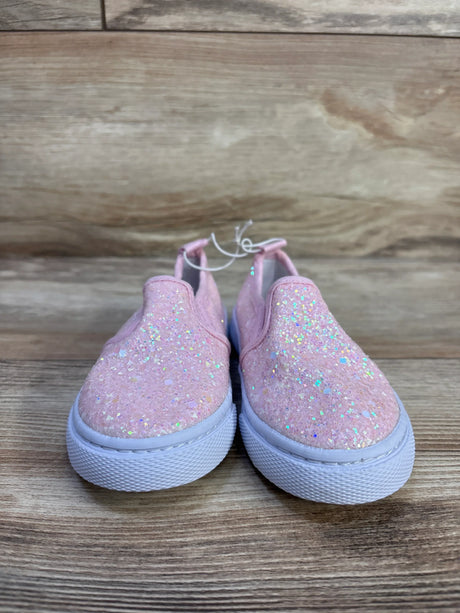 Front view of Cat & Jack Yana toddler slip-on sneakers with pink glitter upper and white rubber sole on wood background