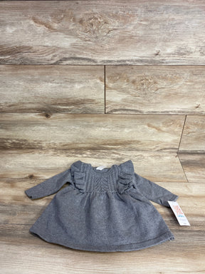 Gray knit baby dress with ruffle details and long sleeves, displayed on wood floor
