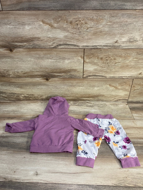 Flat lay of 2-piece baby hoodie and pants set: purple hoodie and white floral pants with purple cuffs on wood background