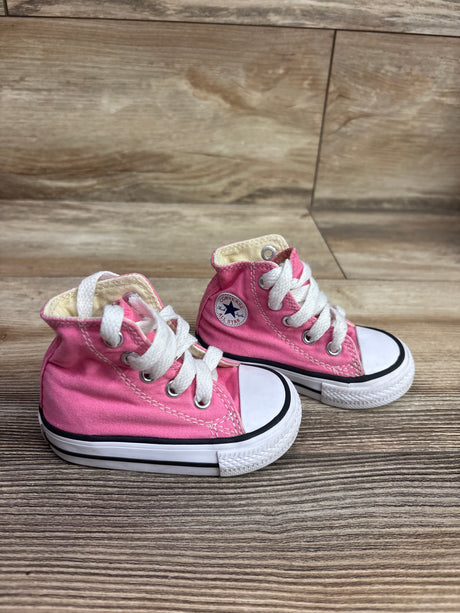Pink Converse Chuck Taylor All Star high top sneakers, front view showing white laces and rubber toe caps on a wood floor
