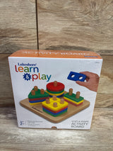 Front view of Sort-A-Shape activity board showing wooden peg board and colorful stacked shapes on a wood surface