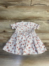 Baby girl's short sleeve floral dress with red flowers on a light background, laid flat on wood