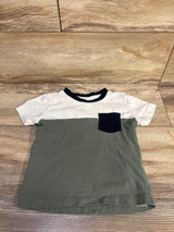 Flat lay of Pekkle 3T short-sleeve pocket shirt showing olive green body, white top, navy collar and pocket on wood floor