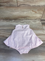 Flat-lay front of pink polka-dot baby bodysuit dress showing elastic leg openings and side skirt panels on wood floor