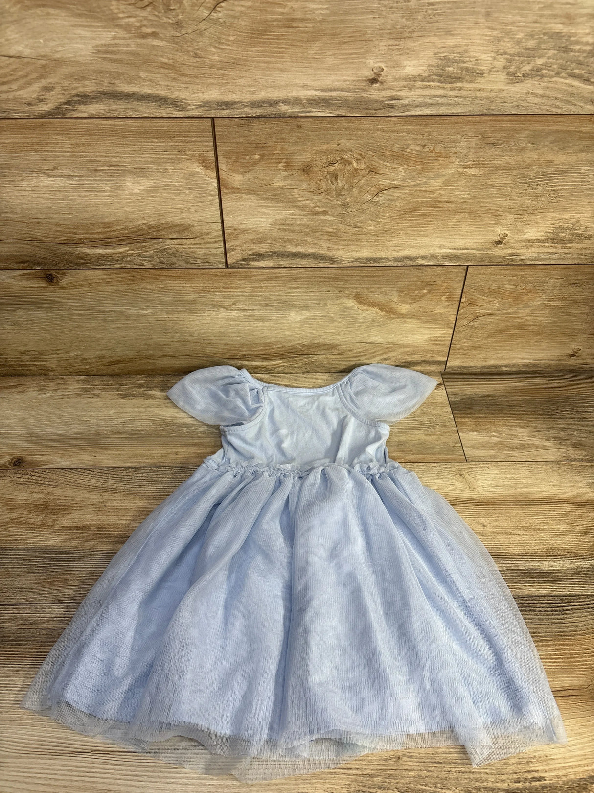 Flat lay of Cat & Jack blue girls' tulle dress with puff sleeves and layered skirt on wood floor