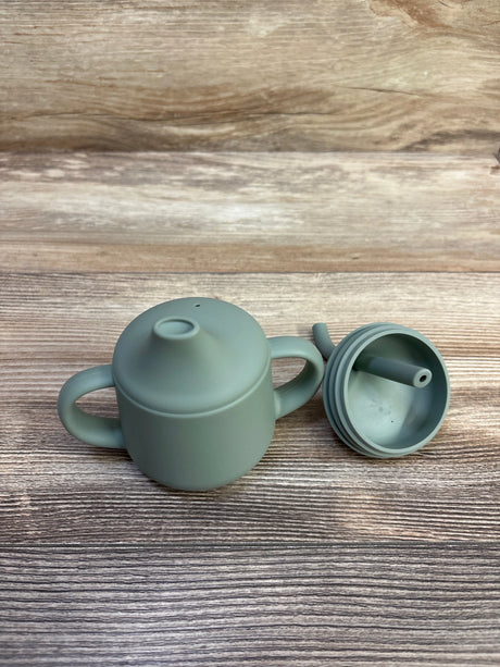 Front view of Moonkie First-Stage 4 oz green sippy cup showcasing two handles and removable screw-on straw lid on wood background
