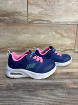Navy blue and pink Skechers toddler sneakers with velcro straps, white soles, and air cushion detail on wood floor